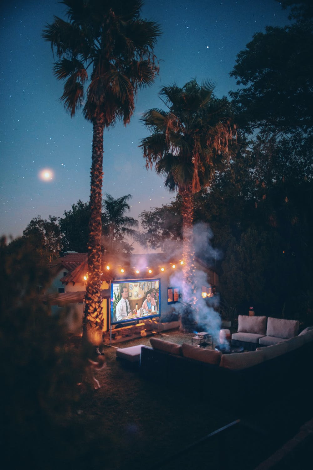 An image of a movie playing on a projector in the backyard at night