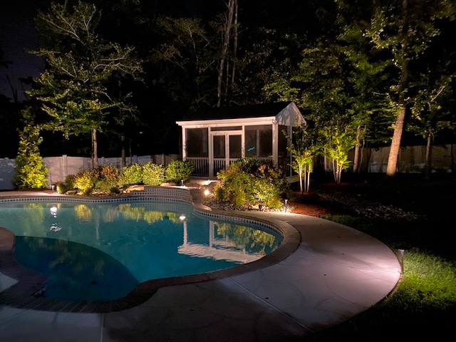 Soft outdoor lighting reflecting across a peaceful pool in a Virginia backyard.