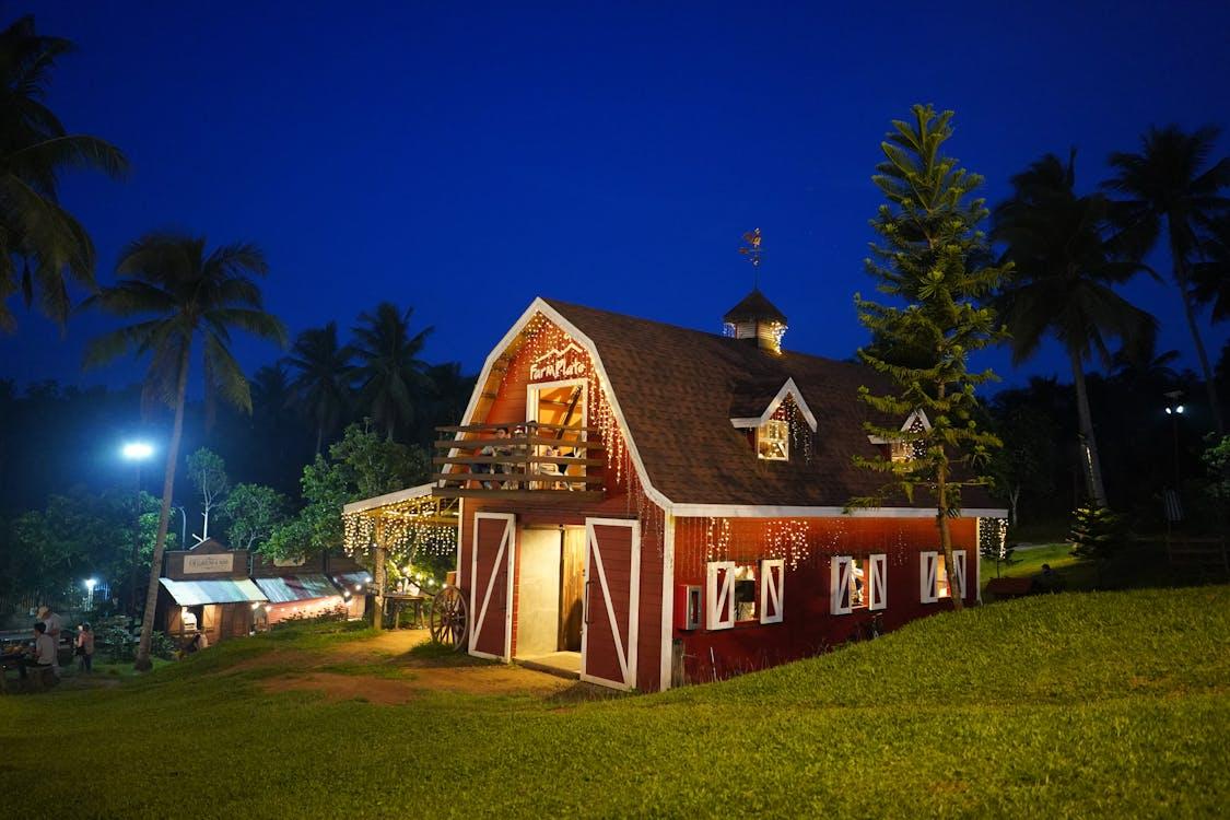 A brown wooden lit-up farmhouse at dusk